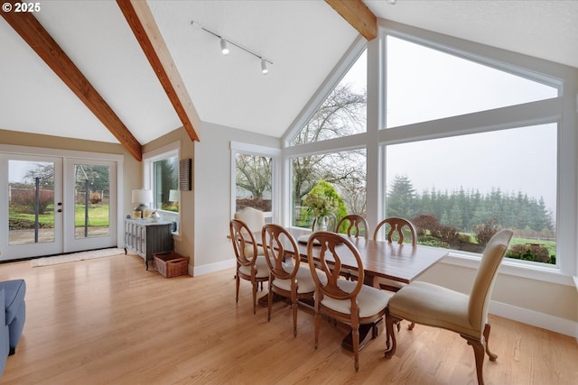 sunroom with lofted ceiling with beams, a healthy amount of sunlight, and french doors