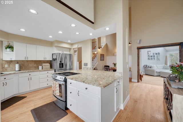 kitchen featuring white cabinetry, appliances with stainless steel finishes, light hardwood / wood-style floors, and light stone counters