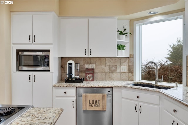 kitchen with sink, appliances with stainless steel finishes, white cabinetry, light stone counters, and tasteful backsplash