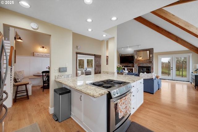 kitchen with white cabinetry, electric range, light hardwood / wood-style floors, light stone countertops, and kitchen peninsula