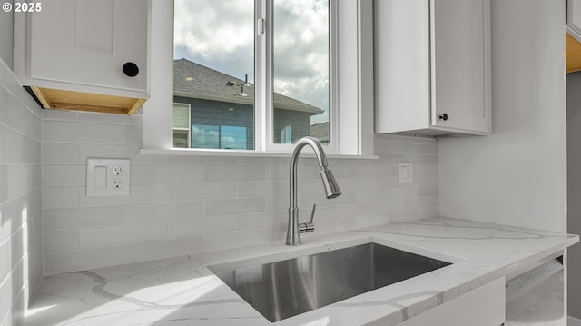 kitchen with light stone countertops, decorative backsplash, sink, dishwasher, and white cabinetry