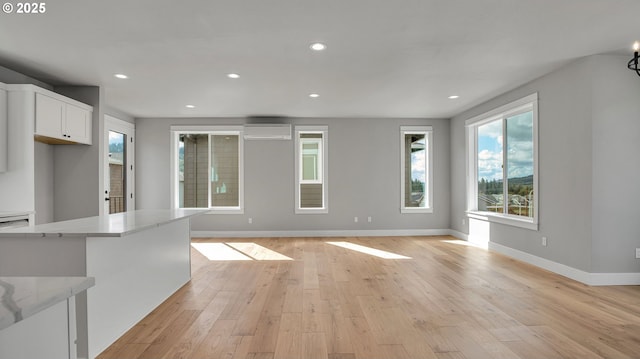 unfurnished living room with a wall unit AC and light hardwood / wood-style floors