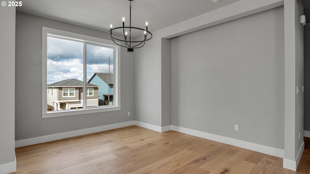 unfurnished dining area with a notable chandelier, plenty of natural light, and light hardwood / wood-style flooring