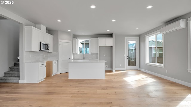 kitchen featuring backsplash, white cabinetry, a kitchen island, and a wall mounted AC