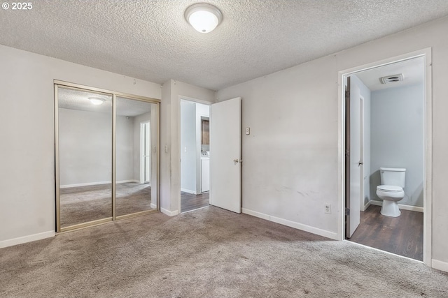 unfurnished bedroom featuring ensuite bath, a closet, and a textured ceiling