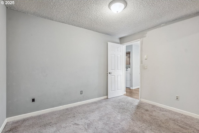 empty room featuring washer / dryer, carpet, and a textured ceiling