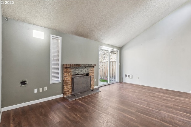 unfurnished living room featuring lofted ceiling, dark hardwood / wood-style flooring, a brick fireplace, and a textured ceiling