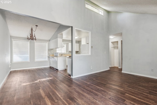 unfurnished living room featuring dark wood-type flooring, sink, a chandelier, high vaulted ceiling, and a textured ceiling