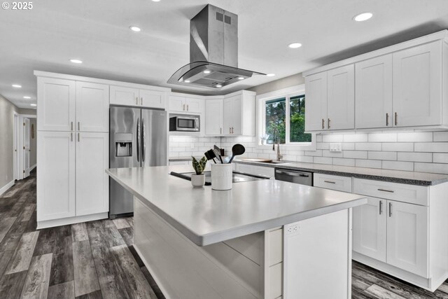 2034 45th St, Florence, OR 97439 - kitchen with stainless steel appliances, tasteful backsplash, dark wood-type flooring, white cabinetry, and island range hood