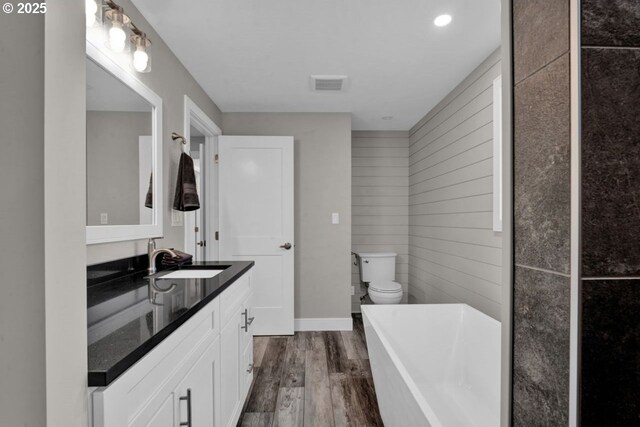 2034 45th St, Florence, OR 97439 - bathroom featuring toilet, vanity, wood finished floors, visible vents, and a freestanding bath