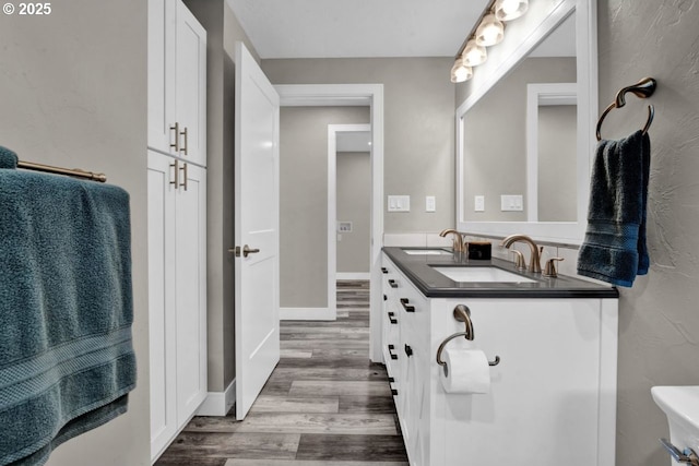 2034 45th St, Florence, OR 97439 - bathroom with baseboards, double vanity, a sink, and wood finished floors
