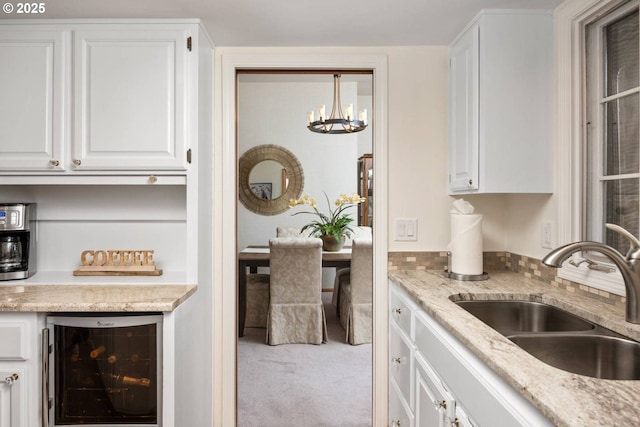 863 Fairway View Dr, Eugene, OR 97401 - kitchen with wine cooler, a sink, carpet, white cabinets, and a chandelier