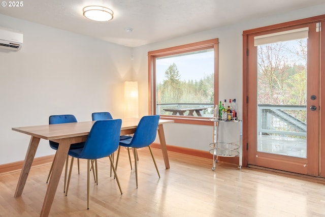 dining area with wood finished floors, baseboards, a wealth of natural light, and a wall mounted AC