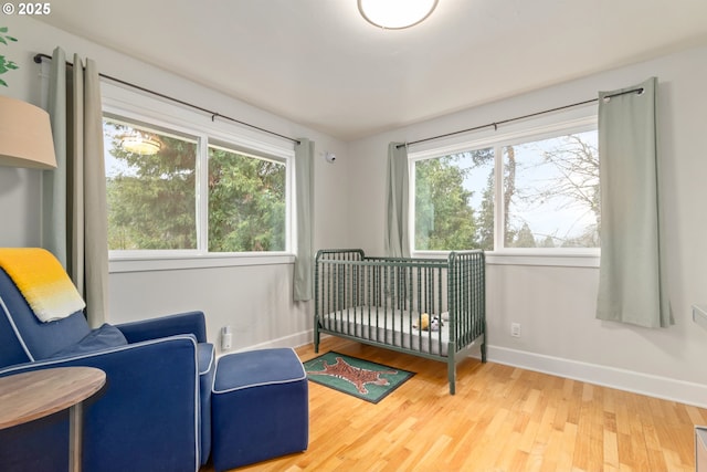 bedroom featuring a crib, wood finished floors, and baseboards