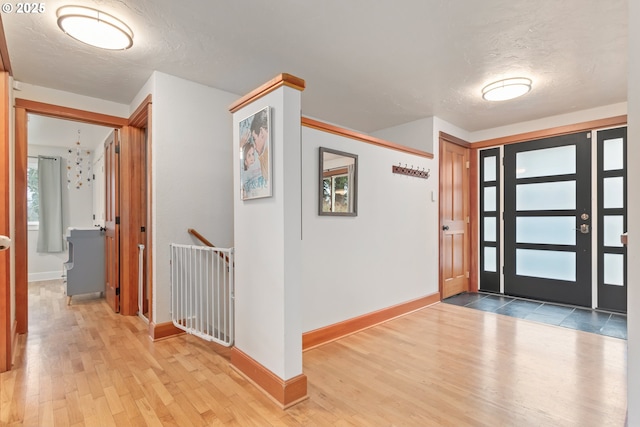 foyer entrance with wood finished floors, baseboards, and a textured ceiling