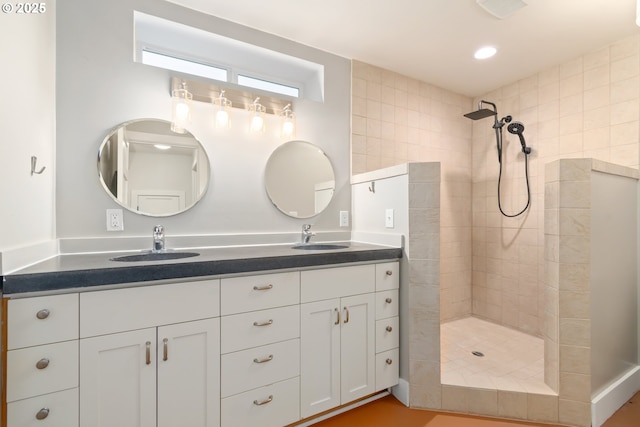 bathroom with a sink, recessed lighting, double vanity, and a tile shower