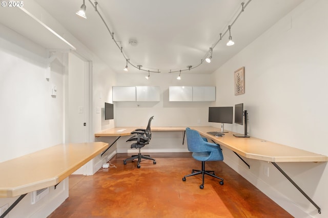 home office featuring track lighting, concrete floors, and built in study area