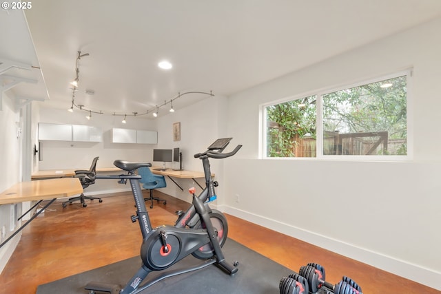 exercise room with track lighting and baseboards