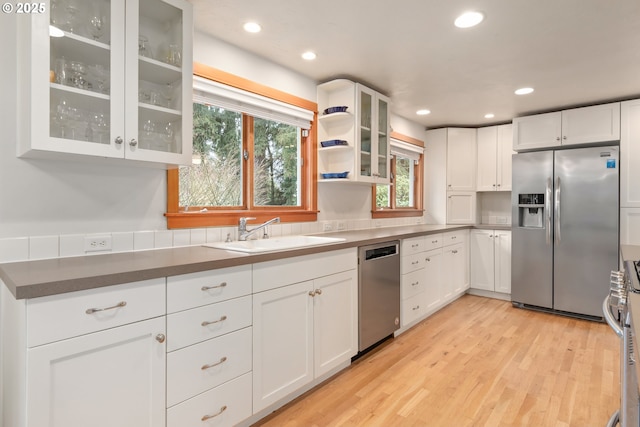 kitchen with a sink, recessed lighting, stainless steel appliances, light wood-style floors, and white cabinets