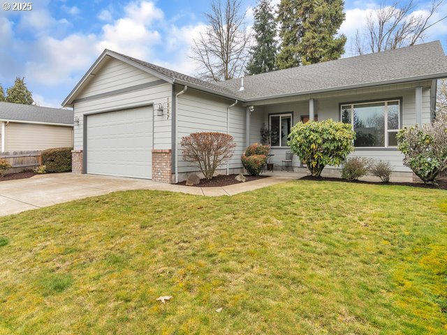 ranch-style home featuring a garage, brick siding, concrete driveway, roof with shingles, and a front yard