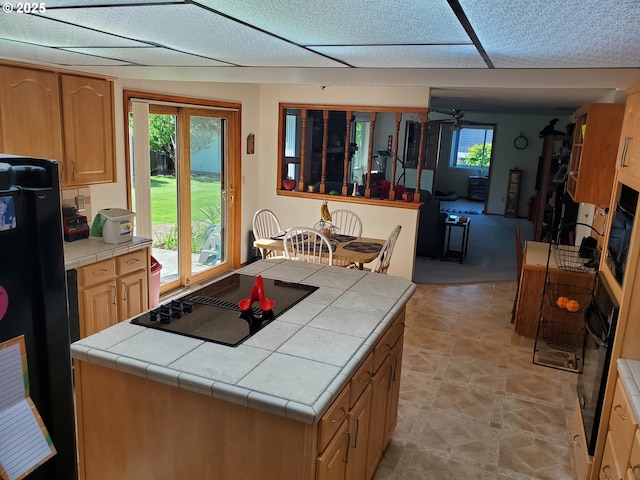 kitchen featuring tile countertops, black appliances, plenty of natural light, and a center island