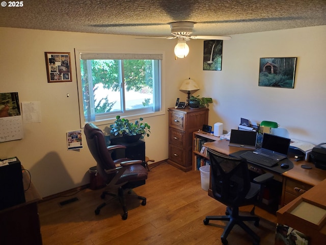 office area with light wood-type flooring, ceiling fan, and a textured ceiling