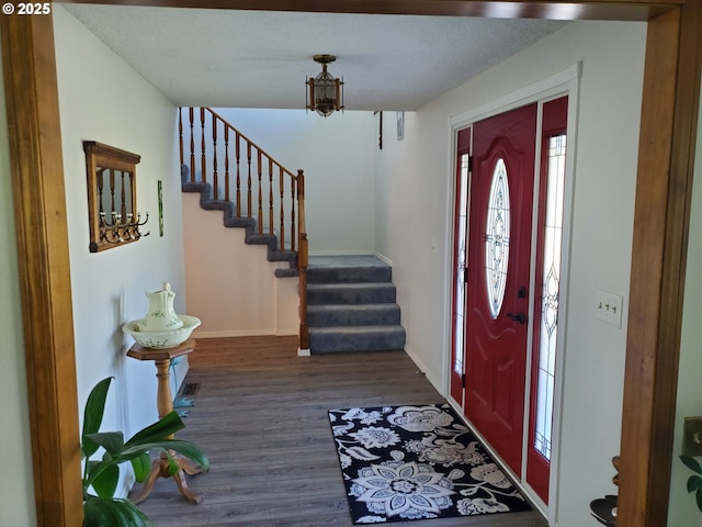 entrance foyer featuring dark wood-style floors, stairway, a chandelier, and baseboards