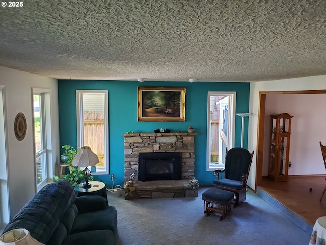 carpeted living room featuring a stone fireplace and a textured ceiling