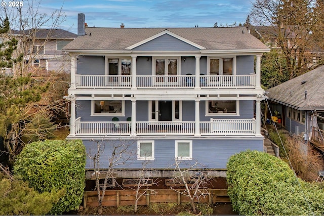 rear view of property with a balcony, a shingled roof, a porch, and french doors