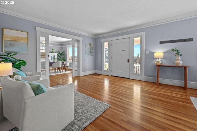 foyer featuring baseboards, wood finished floors, and crown molding