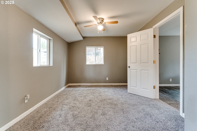 carpeted spare room with vaulted ceiling, ceiling fan, and a wealth of natural light