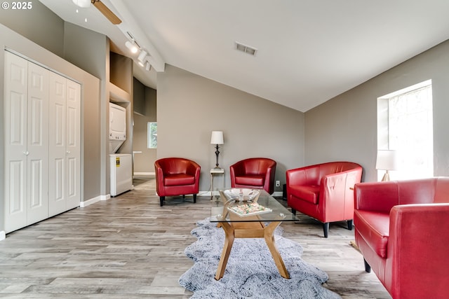 sitting room with stacked washing maching and dryer, ceiling fan, track lighting, and light wood-type flooring