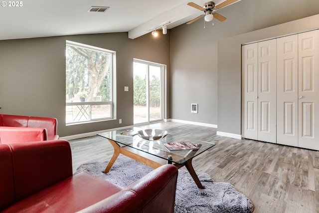 living room with ceiling fan, light hardwood / wood-style flooring, track lighting, and vaulted ceiling with beams