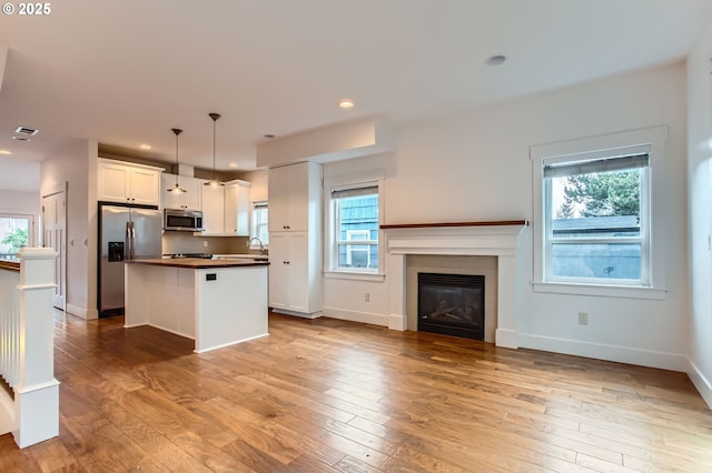 kitchen featuring appliances with stainless steel finishes, open floor plan, visible vents, and light wood-style floors