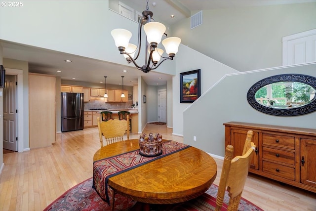 dining space with an inviting chandelier, high vaulted ceiling, recessed lighting, light wood-type flooring, and visible vents
