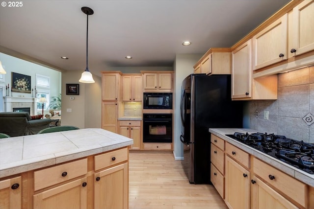 kitchen featuring light brown cabinetry, backsplash, black appliances, and light wood-type flooring