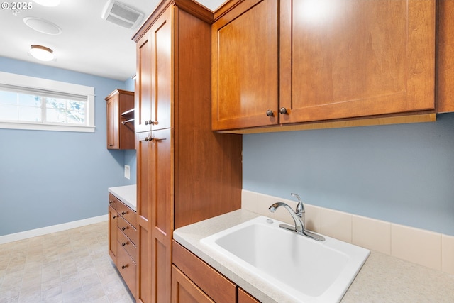 3646 SW Baird St Unit 3, Portland, OR 97219 - kitchen featuring a sink, brown cabinetry, light countertops, and baseboards