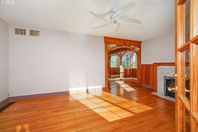 unfurnished living room with ceiling fan, a fireplace, and light wood-type flooring