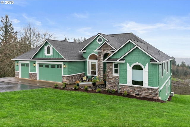 craftsman house featuring a front yard, stone siding, an attached garage, a shingled roof, and driveway