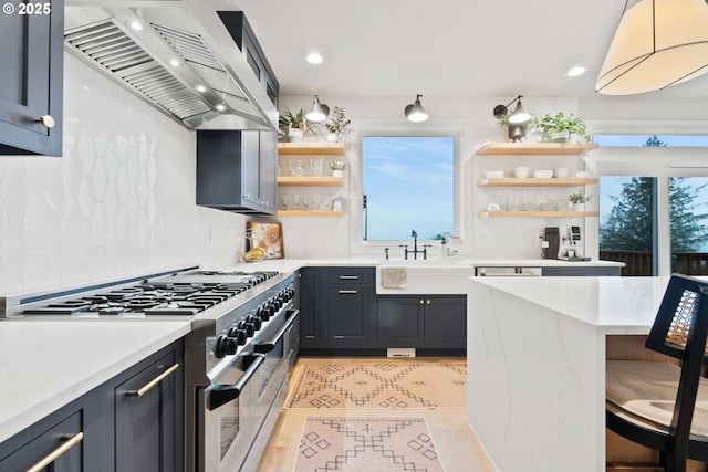 kitchen with open shelves, a sink, wall chimney range hood, light countertops, and double oven range