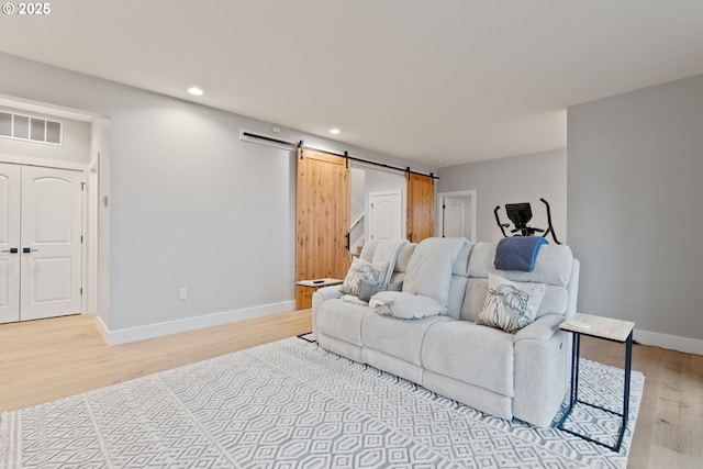 living room with light wood-type flooring, visible vents, a barn door, recessed lighting, and baseboards