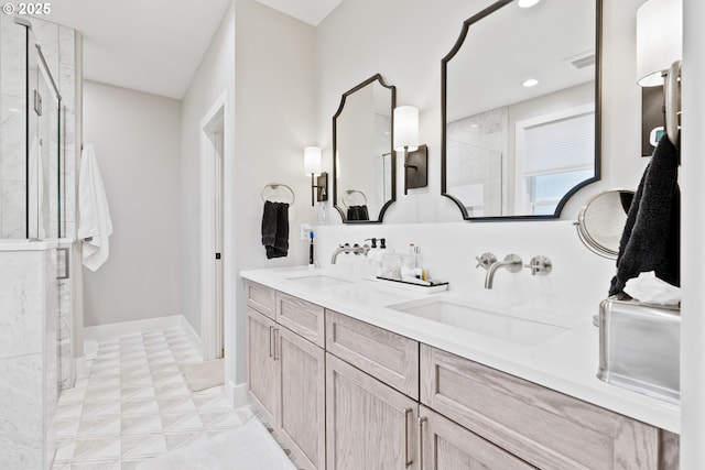 full bath with a stall shower, double vanity, a sink, and baseboards