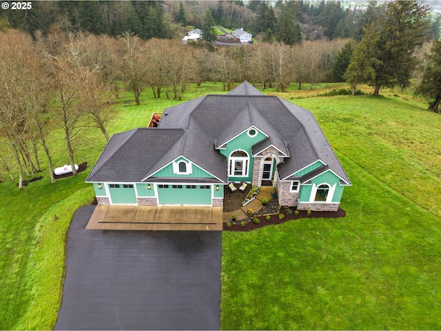view of front of house with a front yard, a shingled roof, an attached garage, stone siding, and aphalt driveway