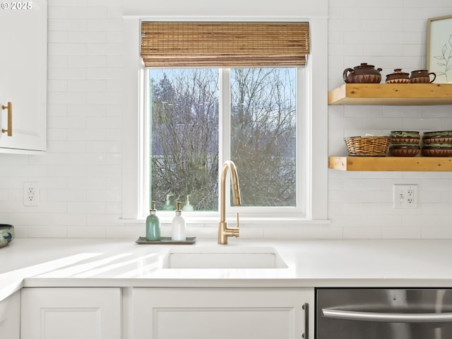 kitchen featuring sink, stainless steel dishwasher, white cabinets, and backsplash