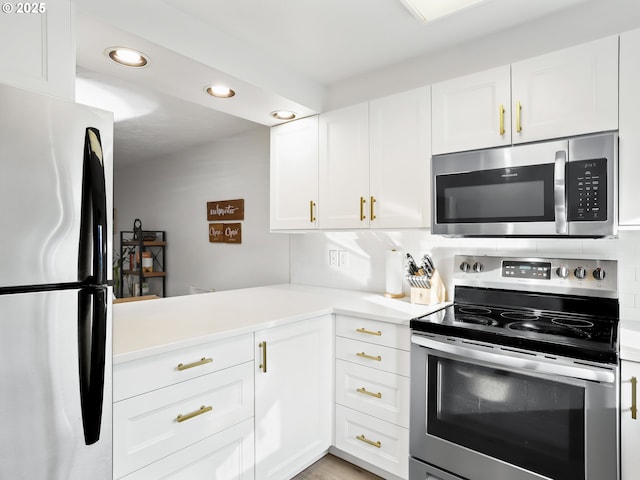 kitchen featuring backsplash, stainless steel appliances, kitchen peninsula, and white cabinets