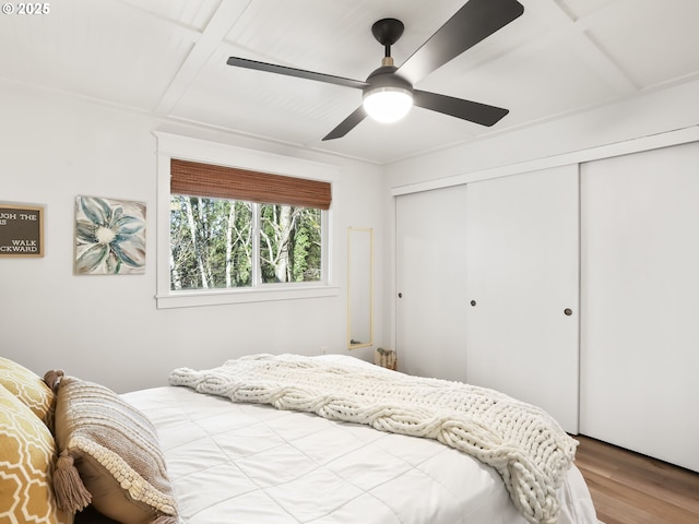 bedroom with hardwood / wood-style flooring, ceiling fan, beam ceiling, coffered ceiling, and a closet