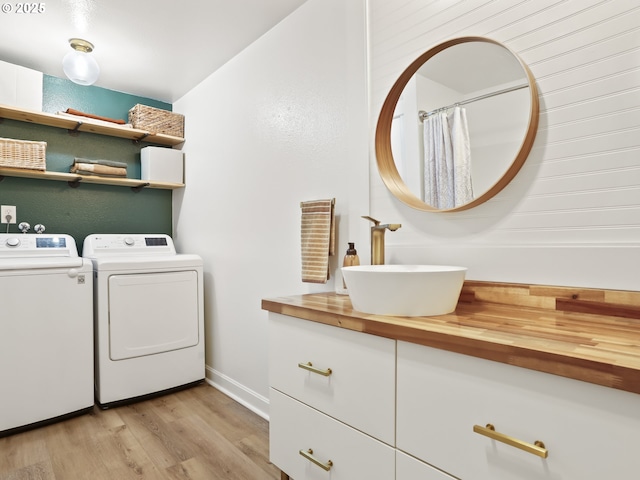 laundry room featuring light hardwood / wood-style flooring, sink, washer and clothes dryer, and cabinets