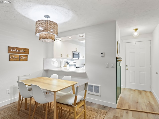 dining area featuring a textured ceiling, an inviting chandelier, and light hardwood / wood-style flooring