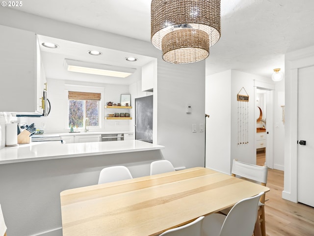 dining area with sink, light hardwood / wood-style floors, and a chandelier