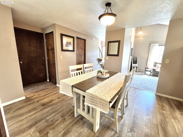 dining space featuring baseboards, a textured ceiling, and wood finished floors